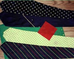 Sono disposti le due stoffe di cravatte cucite e stirate e un quadratto di stoffa per realizzare il gancio.